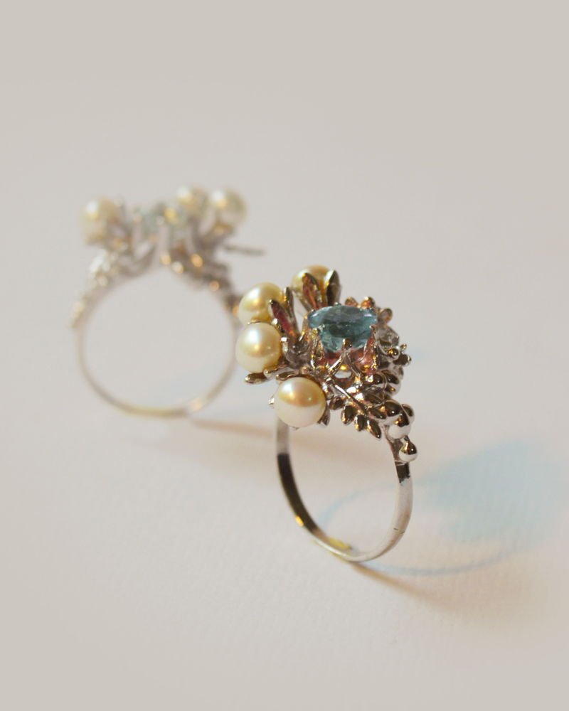A Lei ring in silver with a pale aquamarine crystal set among cast leaves and pearls.