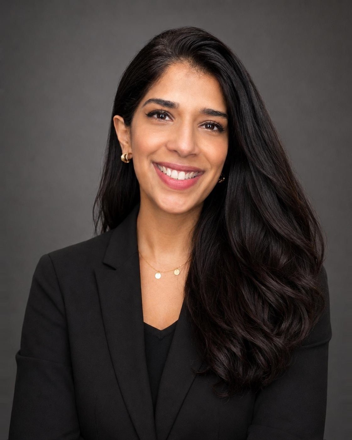 Sana Aziz, photographed in a black jacket against a dark grey ground.