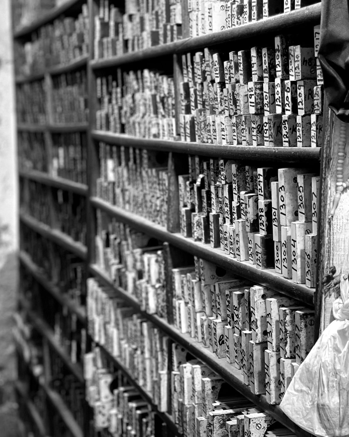 Shelves holding rows of labelled metal pattern stamps.